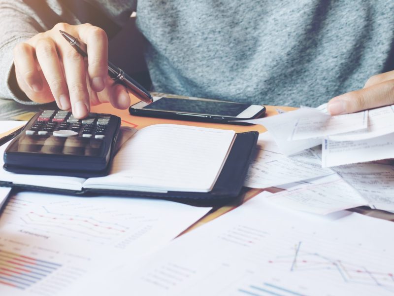 Man using calculator and calculate bills in home office.