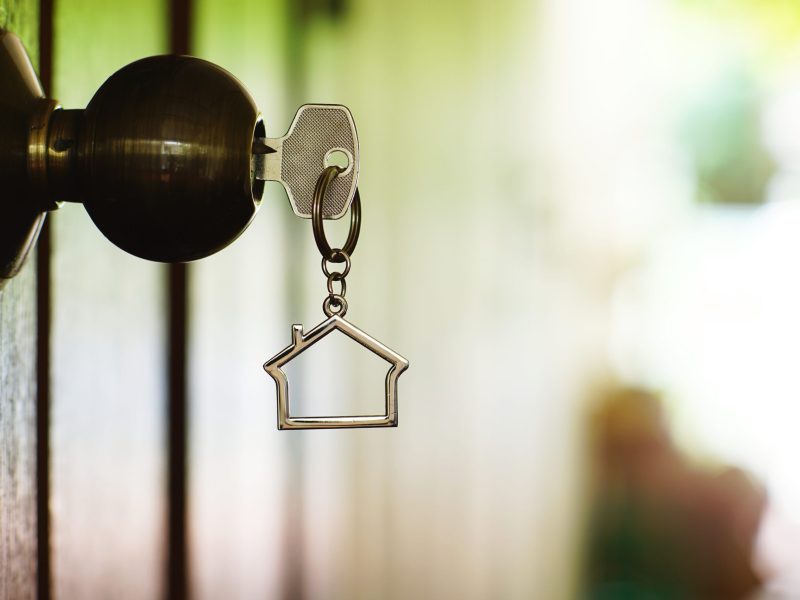 Home key with house keyring in keyhole, copy space, property concept