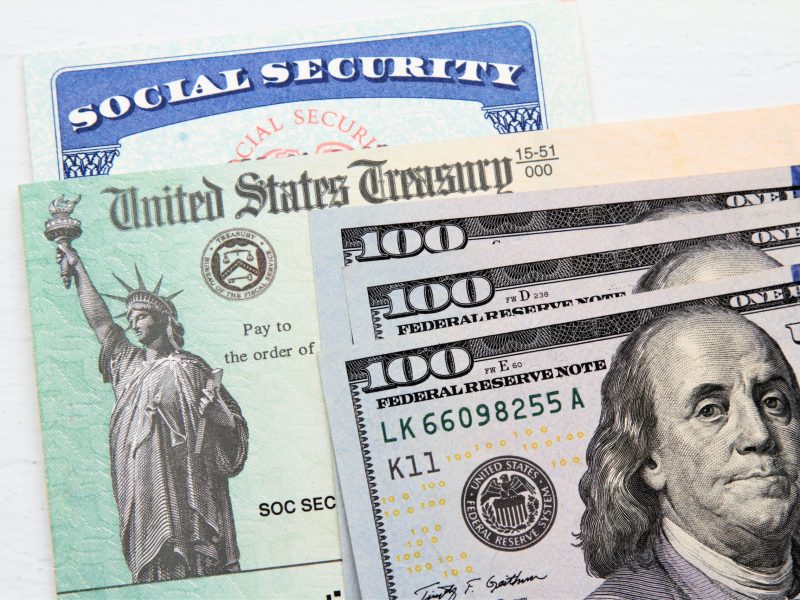 Partial view of Social Security card, US Treasury checks and hundred dollar bills. Finance and retirement concept.