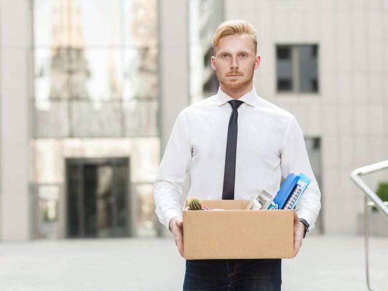Youre fired. Unhappy bearded business man going out with cardboard, looking at camera and feeling looser. Outdoor